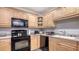 Functional kitchen features light wood cabinets, black appliances, and laminate countertops at 7272 Cass Cir, Sarasota, FL 34231