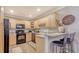Well-lit kitchen with wooden cabinets, a black stove, a microwave, and a breakfast bar with chairs at 7272 Cass Cir, Sarasota, FL 34231