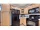Efficient kitchen with light wood cabinets, black appliances, and laminate countertops at 7272 Cass Cir, Sarasota, FL 34231