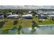 Aerial view of a single-story home featuring a covered carport, mature palm trees, and landscaping near a lake at 8449 Imperial Cir, Palmetto, FL 34221
