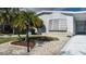 Home featuring well-maintained landscaping with white rock, mature palms, and a clear address marker at 8449 Imperial Cir, Palmetto, FL 34221