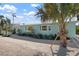 Cozy turquoise home with a well-manicured garden, quaint bay windows, and a palm tree-lined gravel driveway at 912 N Shore Dr, Anna Maria, FL 34216