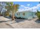 Charming turquoise home with a palm tree and gravel driveway offers a tranquil coastal living experience at 912 N Shore Dr, Anna Maria, FL 34216