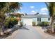 Exterior view of the light blue house showing garage, lush landscaping, and long driveway at 912 N Shore Dr, Anna Maria, FL 34216
