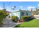 Charming exterior of a light blue home showcasing lush landscaping, palm trees and a welcoming walkway at 912 N Shore Dr, Anna Maria, FL 34216