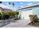 View of the home's garage, showcasing a paved driveway, tropical landscaping, and convenient access at 912 N Shore Dr, Anna Maria, FL 34216