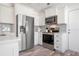 Bright kitchen with stainless steel appliances, white cabinets, grey backsplash and wood-look flooring at 912 N Shore Dr, Anna Maria, FL 34216
