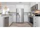 Bright kitchen with stainless steel appliances, white cabinets, grey backsplash and wood-look flooring at 912 N Shore Dr, Anna Maria, FL 34216