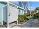 Side yard of light blue house featuring outdoor shower, lawn chairs, lush landscaping and paver walkway at 912 N Shore Dr, Anna Maria, FL 34216