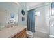This bathroom has a vanity with a stone countertop, a toilet and a bathtub with a blue shower curtain at 1407 Morning Sky Gln, Bradenton, FL 34208