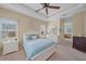Cozy bedroom featuring a tray ceiling, ceiling fan, and views to the ensuite bathroom at 1407 Morning Sky Gln, Bradenton, FL 34208