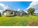 The green yard boasts a view of the home's screened-in patio and a lush, tropical landscape at 16741 Ellsworth Ave, Bradenton, FL 34202