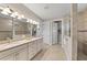 Modern bathroom with double sinks, white cabinets, a large mirror, and tile flooring at 16741 Ellsworth Ave, Bradenton, FL 34202