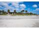 Picturesque sandy beach with a gazebo and palm trees under a beautiful blue, cloudy sky at 222 Pine Glen Ct, Englewood, FL 34223