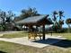 A yellow picnic table sits beneath a pavilion with metal roof on a concrete pad at the park at 222 Pine Glen Ct, Englewood, FL 34223