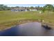 Home exterior featuring a pond, large manicured lot, well-kept lawn, and a matching garage at 25605 69Th E Ave, Myakka City, FL 34251