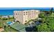 Beautiful aerial view of condo building with tennis court, lush landscaping, and private beach access at 2675 Gulf Of Mexico Dr # 301, Longboat Key, FL 34228