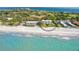 An aerial view of a beachfront condo with a community pool, lush landscaping, and a pristine sandy beach on the Gulf of Mexico at 2675 Gulf Of Mexico Dr # 301, Longboat Key, FL 34228