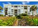Condo building with balconies, lush landscaping, and a private boardwalk leading to a sandy beach at 2675 Gulf Of Mexico Dr # 301, Longboat Key, FL 34228