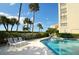 Lovely pool area with lounge chairs, lush landscaping, and a partial view of the nearby condo building at 2675 Gulf Of Mexico Dr # 301, Longboat Key, FL 34228