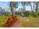Secluded backyard featuring a stone bench amidst colorful plants, leading to a screened-in porch at 28 Tall Trees Ct, Sarasota, FL 34232