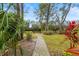 Scenic backyard featuring a gravel pathway leading to a bench, surrounded by lush landscaping at 28 Tall Trees Ct, Sarasota, FL 34232