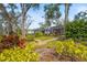 Backyard view of the screened-in patio with a stone bench surrounded by colorful landscaped elements at 28 Tall Trees Ct, Sarasota, FL 34232