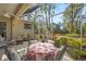 Comfortable screened patio with outdoor furniture, floral tablecloth, and well-maintained landscaping at 28 Tall Trees Ct, Sarasota, FL 34232