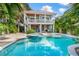 Beautiful backyard showcasing a pool, spa, and multi-level home with a spiral staircase amid tropical foliage at 418 Magnolia Ave, Anna Maria, FL 34216