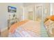 Light-filled bedroom boasts wood-look floors, a TV, and a soft, decorative coral-themed comforter at 418 Magnolia Ave, Anna Maria, FL 34216