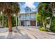 Beautiful two-story home with blue siding, white trim, and a second-story balcony, surrounded by lush, tropical landscaping at 418 Magnolia Ave, Anna Maria, FL 34216