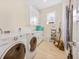Well-lit laundry room offers white cabinets, a window, and a washer and dryer at 418 Magnolia Ave, Anna Maria, FL 34216