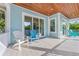 Outdoor porch with blue siding, bright white trim, light-colored floor tiles, and matching blue chairs at 418 Magnolia Ave, Anna Maria, FL 34216