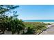 View of the ocean through lush green vegetation and a white fence at 4200 Gulf Dr # 101, Holmes Beach, FL 34217