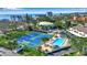 Aerial view of community amenities including a swimming pool, tennis courts, and verdant trees at 4234 Gulf Of Mexico Dr # H2, Longboat Key, FL 34228