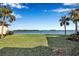 Backyard showing a grass lawn and water in the distance with palm trees on the right side of the frame at 4234 Gulf Of Mexico Dr # H2, Longboat Key, FL 34228