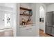 Stylish bar area with a wooden shelf, glassware, and a view into the kitchen and entryway at 4234 Gulf Of Mexico Dr # H2, Longboat Key, FL 34228