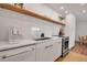 Modern kitchen featuring sleek white cabinets, stainless steel appliances, and a stylish floating shelf at 4234 Gulf Of Mexico Dr # H2, Longboat Key, FL 34228