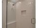 Modern shower with white tile, a glass door, a built-in niche, and a shower bench for added comfort at 4234 Gulf Of Mexico Dr # H2, Longboat Key, FL 34228