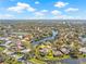 Aerial view of a lakeside neighborhood with lush trees, landscaping, and houses nestled along the waterfront at 4477 White Cedar Trl, Sarasota, FL 34238
