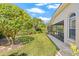 Expansive backyard featuring lush green lawn, mature trees, and a screened-in patio at 4477 White Cedar Trl, Sarasota, FL 34238