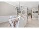 Dining room with a rustic wood table, white upholstered chairs, modern lighting, and a large clock accenting the wall at 4477 White Cedar Trl, Sarasota, FL 34238