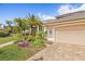 A lovely home with a well-manicured lawn, palm trees, and a brick driveway on a sunny day at 4477 White Cedar Trl, Sarasota, FL 34238