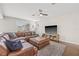 Cozy living room features a large brown leather sectional, ottoman, ceiling fan, and a TV with wood entertainment center at 4477 White Cedar Trl, Sarasota, FL 34238