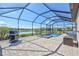 Screened-in pool area with a spa, BBQ, and scenic views of the backyard and lake at 4968 Seafoam Trl, Bradenton, FL 34211