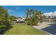 This home has a lush green lawn with tropical trees, a dock, and a seating area overlooking the water at 619 Buttonwood Dr, Longboat Key, FL 34228