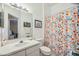 Well-lit bathroom with a floral shower curtain, white vanity, and framed artwork at 6263 Tassleflower Trl, Lakewood Ranch, FL 34202