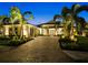 Beautiful home exterior with a brick driveway, lush landscaping, and warm lighting at twilight at 8271 Redonda Loop, Lakewood Ranch, FL 34202