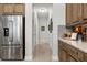 Bright hallway with tile flooring, leading past stainless steel refrigerator and kitchen area at 8271 Redonda Loop, Lakewood Ranch, FL 34202