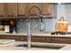 Close-up of a stainless steel kitchen faucet with marble countertops and wooden cabinetry at 8271 Redonda Loop, Lakewood Ranch, FL 34202